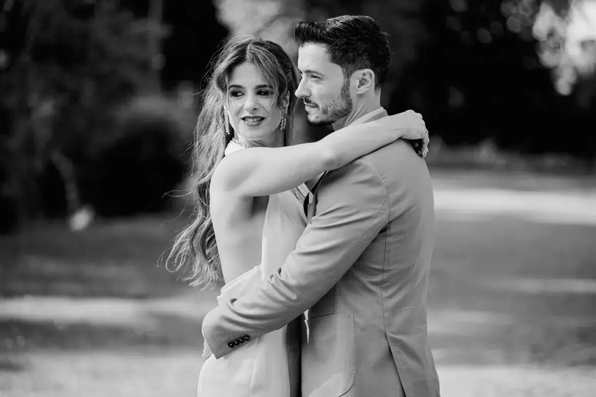 Black and white wedding photo of the bride hugging her groom from behind and resting her head on his shoulder in Luxembourg.