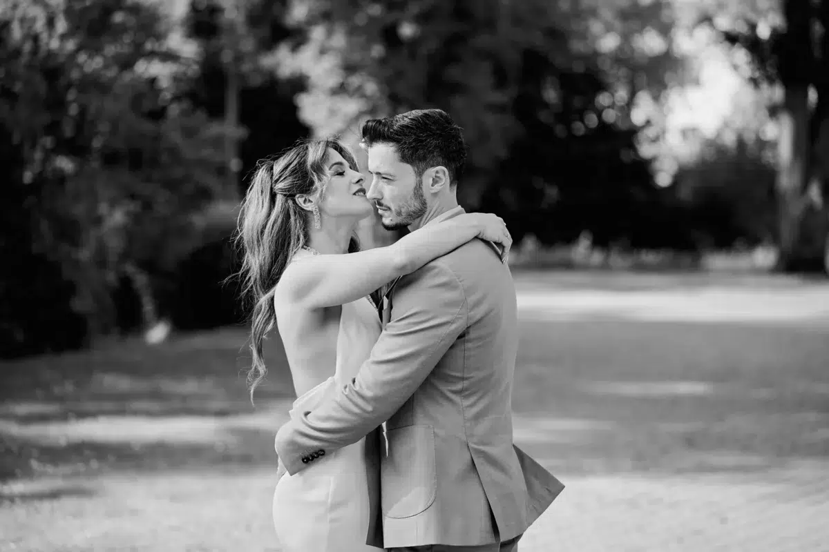 Black and white photograph of a bride and groom in a close embrace on a park path, part of an authentic Luxembourg wedding story.