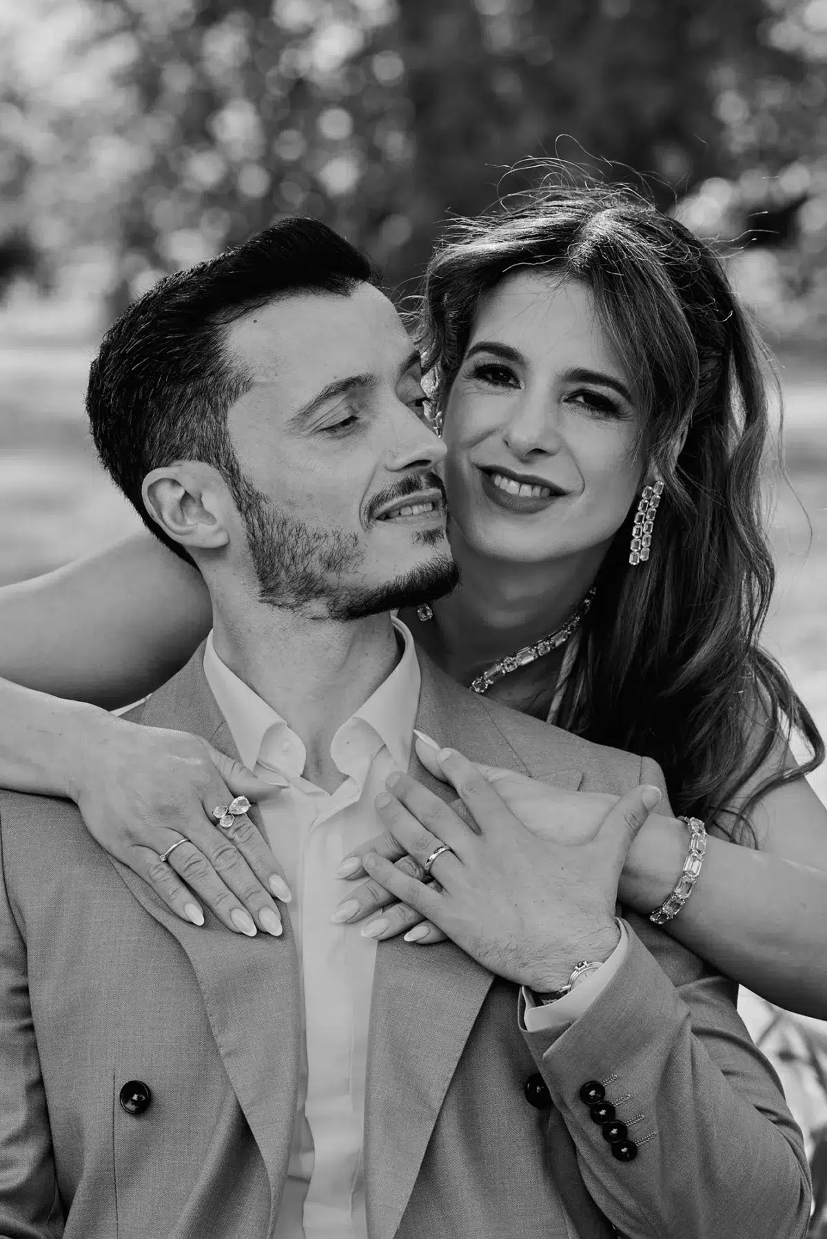 Close black and white portrait showing the bride's hands, wedding ring, and diamond bracelet resting on the groom's chest.
