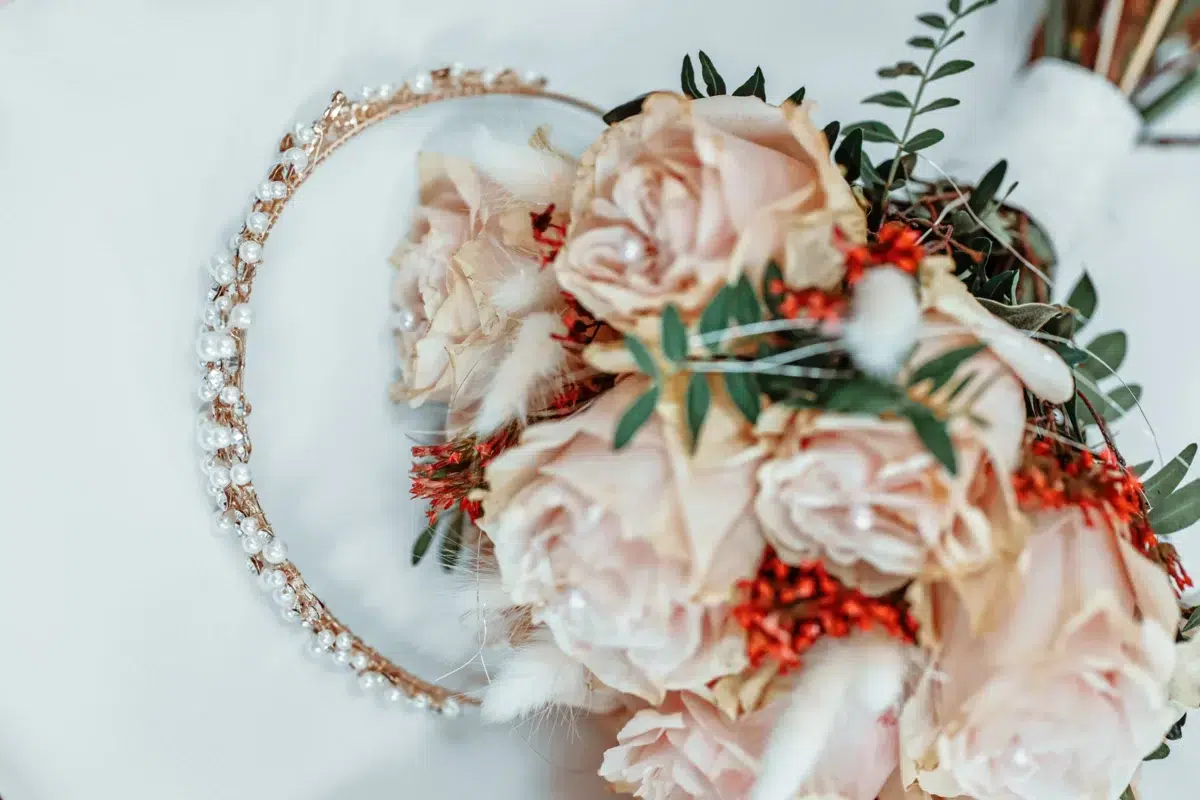 Flat lay detail of a pearl bridal tiara beside a blush rose and dried flower bouquet, styled for a Luxembourg wedding shoot.