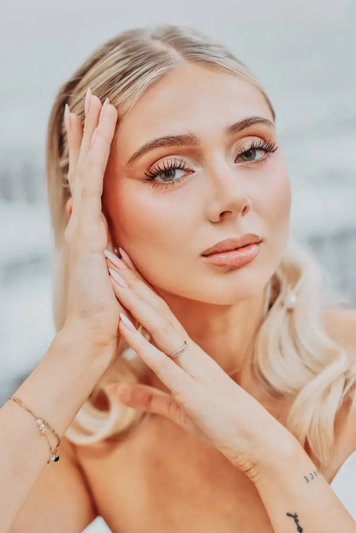 Close beauty portrait of a bride framing her face with her hands, showing her rings and bracelet, Luxembourg bridal photography.