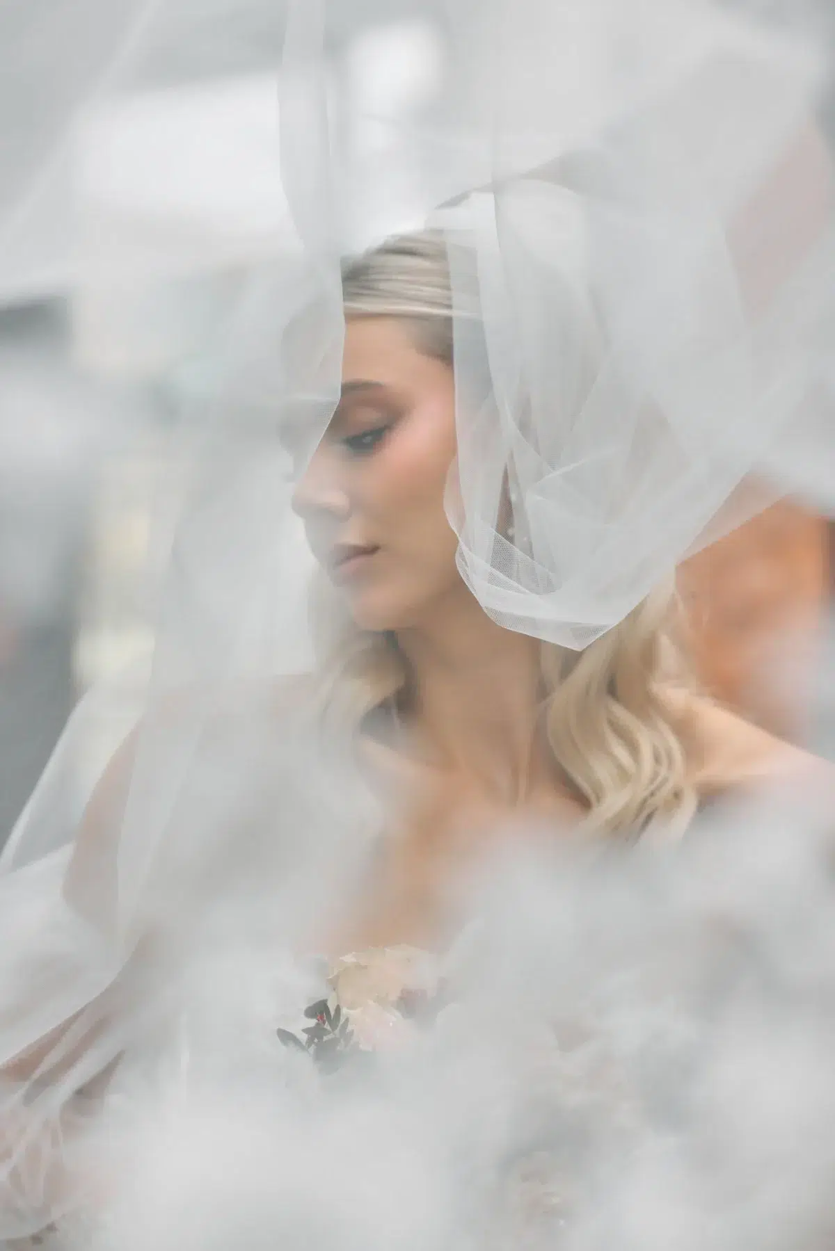 Soft-focus profile portrait of a bride beneath her veil, a quiet dreamy moment from a Luxembourg bridal shoot.