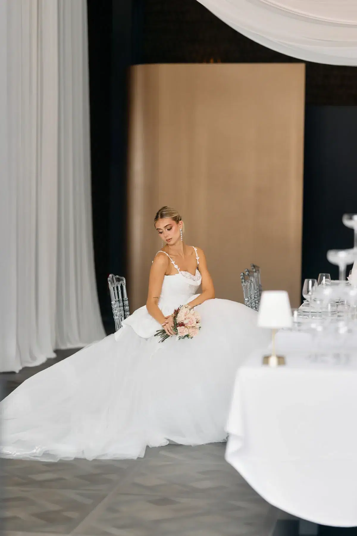 Bride seated at the reception table looking softly down at her bouquet, Luxembourg wedding photography.