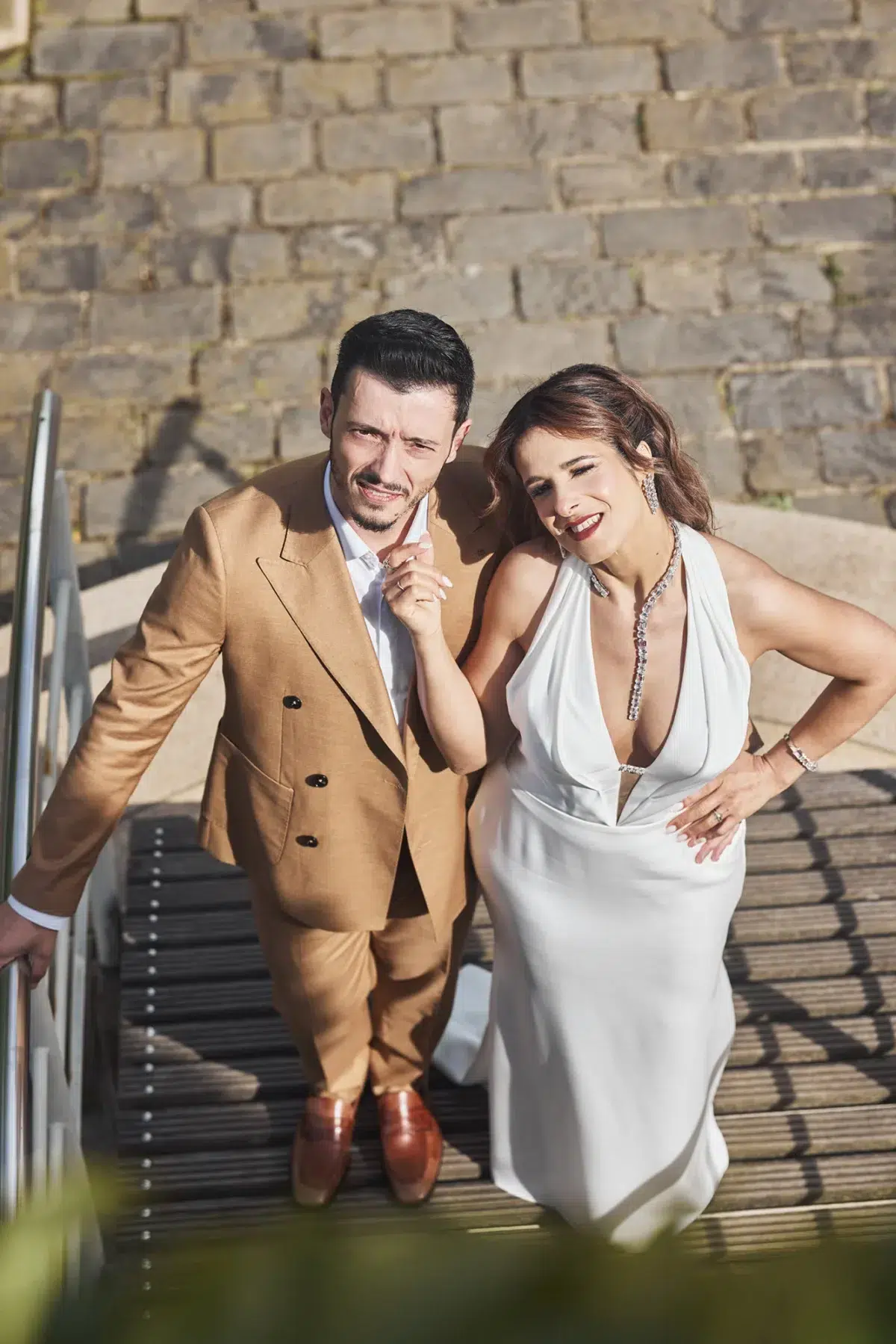 A lighthearted, playful moment between bride and groom on stone steps, capturing the fun and authentic feeling of their wedding day.